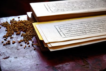 Close up photo of a traditional tibetan prayer book, with seed of grain used during the religion rituals.